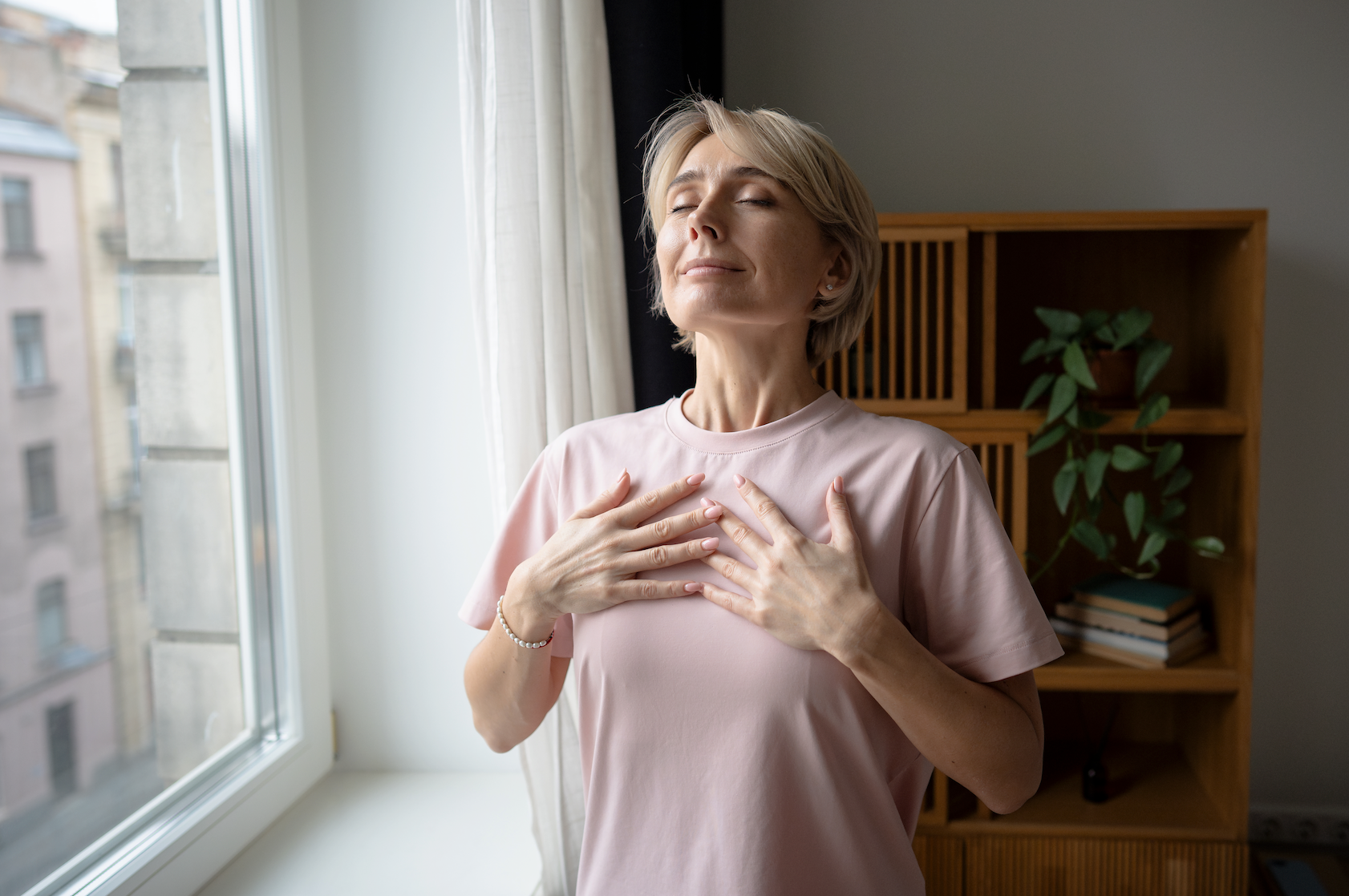 Calm meditating woman beside the window